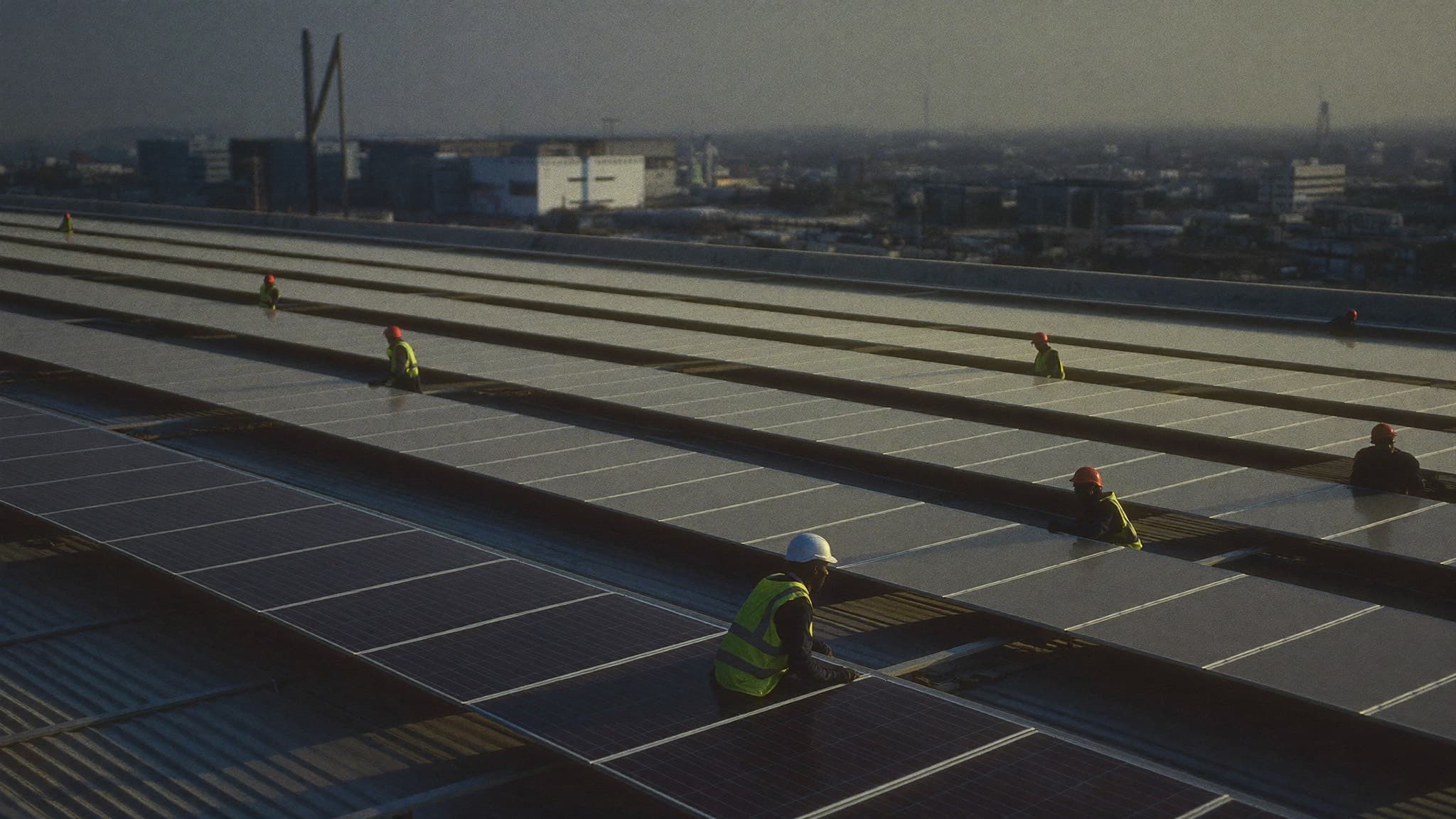 Installers fitting solar panels on a factory roof
