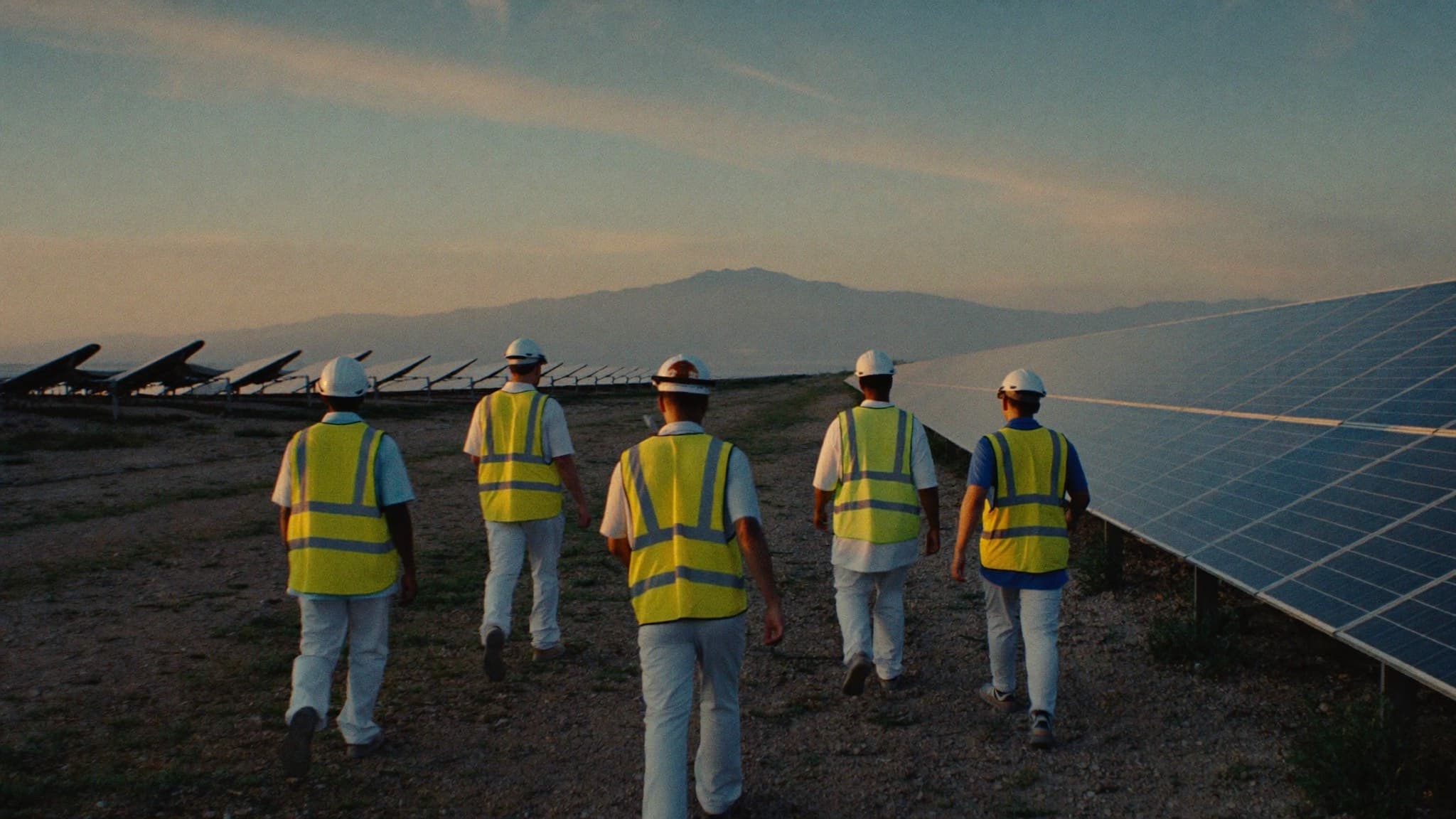 Engineers walking between rows of solar panels at golden hour